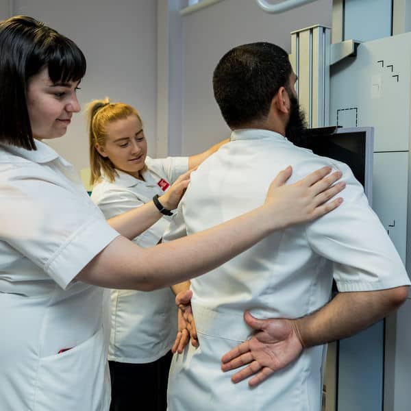 Uniformed students using radiotherapy equipment.