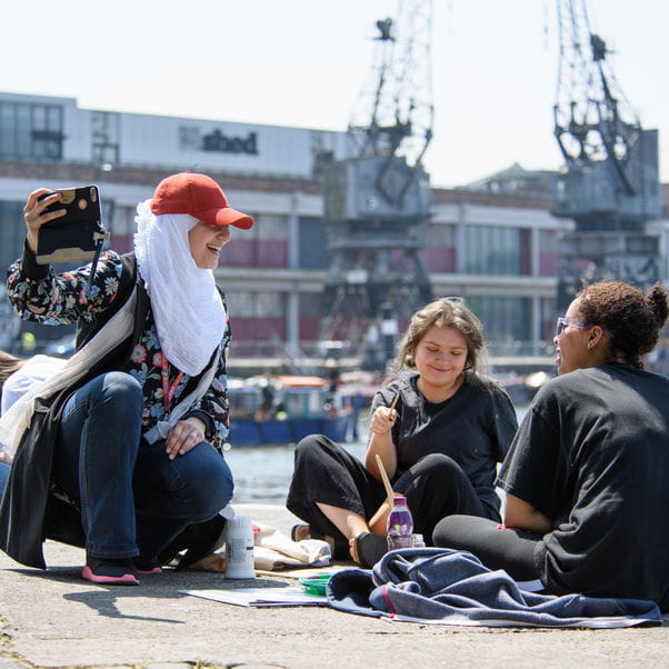 Creative students on Bristol harbourside, taking a photo of themselves