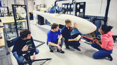 Group of male and female students looking at the bodywork of a glider in the workshop with the tutor.