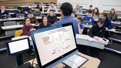 Economics lecturer presenting to students in a lecture theatre