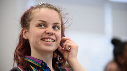 A female student in a classroom, smiling.