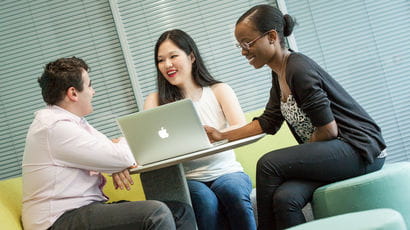 A group of students chatting around a laptop.