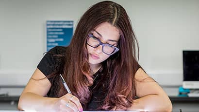 A student drawing with an electronic pen on a lightbox.