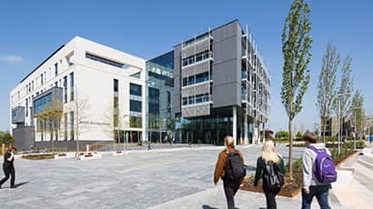 A group of three students walking toward the Bristol Business and Law Schools building.