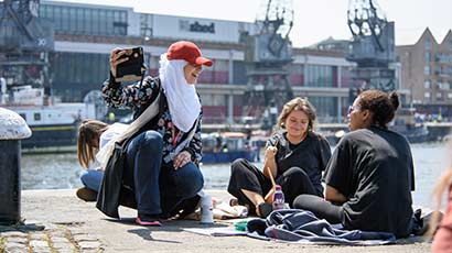 A group of students sat around some art materials by Bristol harbourside.