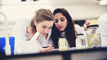 Two students in a laboratory, inspecting an item.