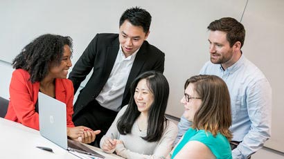 Group of people talking around a computer screen.