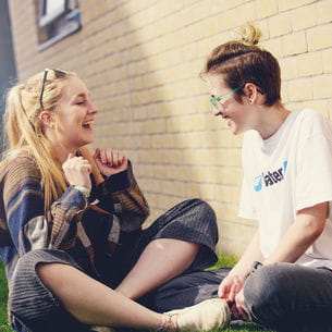 Two students sat outside student accommodation.