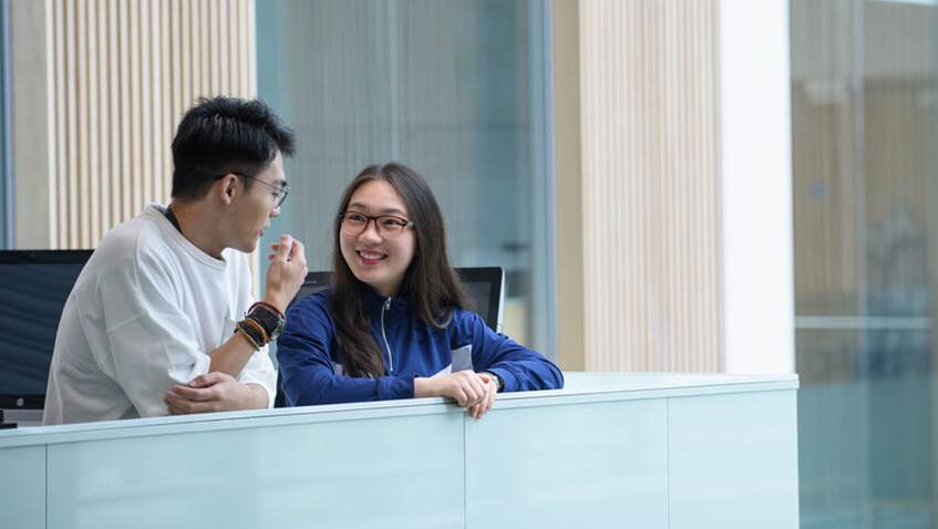 Two international students chatting in the Atrium mezzanine.