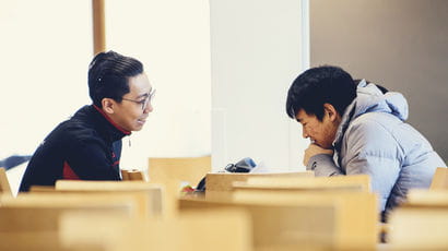 Two students sat opposite each other at a table