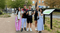 Four students smiling to camera with thumbs up in a green space near Frenchay Campus.