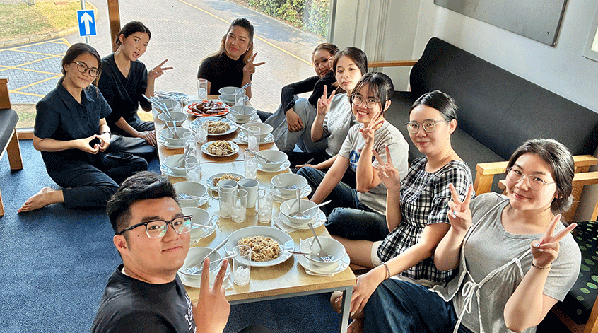 Summer school students sitting around a low table full of food,