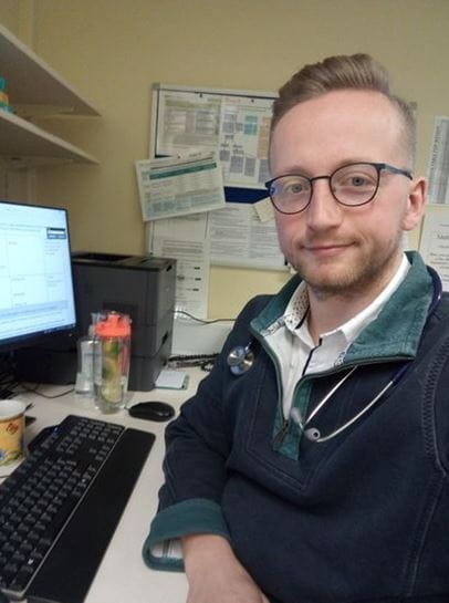 James Wills smile at the camera in his nurse uniform
