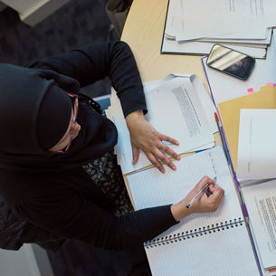 An image of a student in the library taken from above, she's writing in a notepad