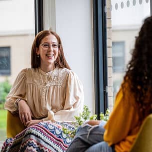 two people talking, one facing the camera and smiling