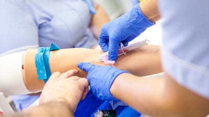 Nursing student being shown how to take blood.