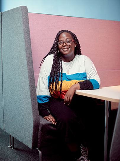 Student Mercedes, sitting in a study space in the Business School, smiling at the camera.