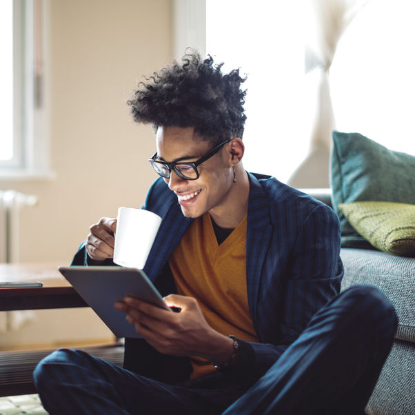 Person sat down with a tablet and a mug.