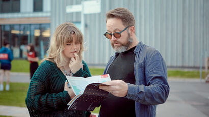 A  prospective student and their supporter look at a Campus guide.