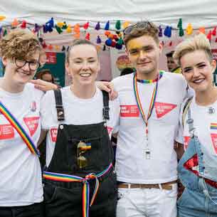 Smiling students in front of rainbow bunting.