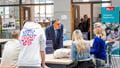 Students and visitors at a large table in the foyer of the Business School talking to a member of staff. 