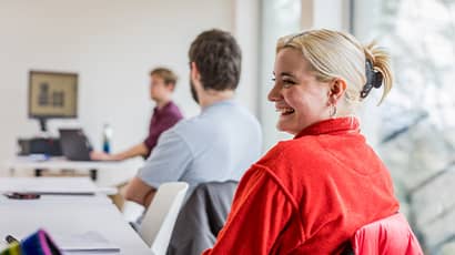 Postgraduate student in classroom smiling.