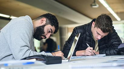 Two students, with a laptop and a notebook