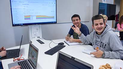 Postgraduate students sat around a screen in a seminar room.