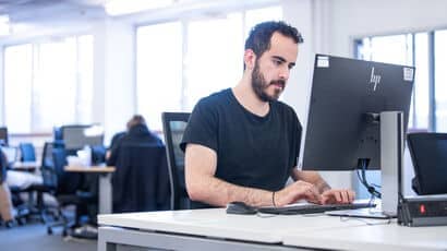 Postgraduate student typing on a computer.