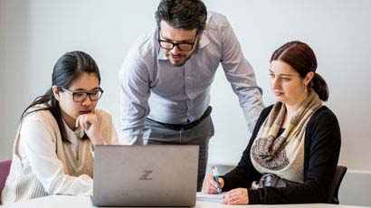 Three CPD students gathered together looking at a laptop.