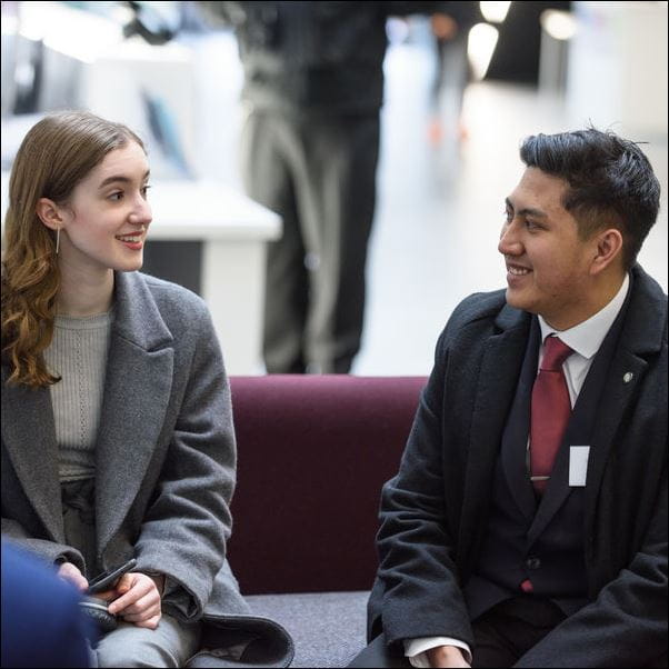 Smartly dressed people talking in an atrium.