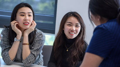 Three people talking in a meeting room.