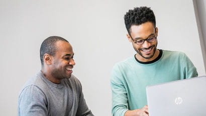 Two people looking at a computer in a study room.