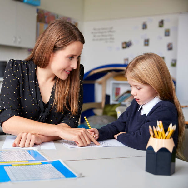 Teacher helping a young child to write.