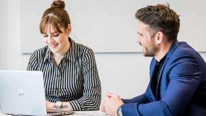 Two people having a discussion over a laptop.