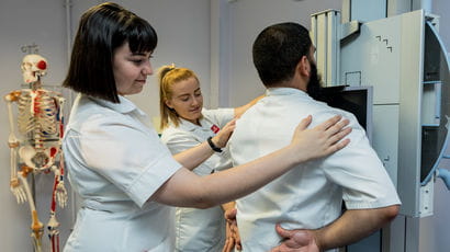 Uniformed students using radiotherapy equipment.