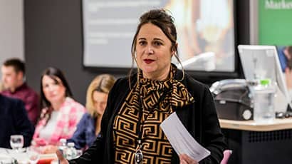 Woman in smart business dress standing and presenting as part of a business workshop.
