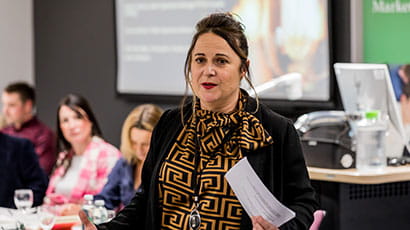 Woman in smart business dress standing and presenting as part of a business workshop.