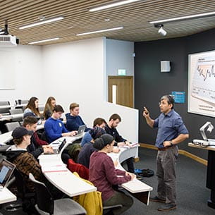 An academic teaching postgraduate students in a lecture theatre