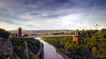 An aerial shot of Clifton Suspension Bridge with hot air balloons.
