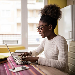 Young woman in white jumper and glasses using laptop at home