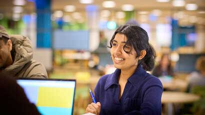 Student smiling at a person over a counter.