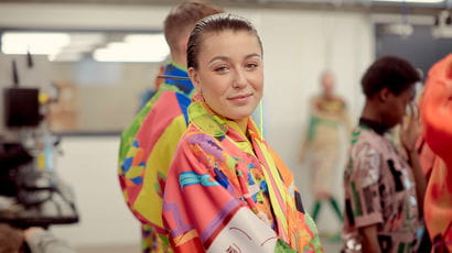 A fashion student looking directly at the camera, wearing a bright outfit