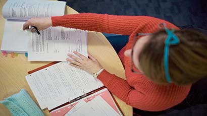 Overhead shot of a woman reading a textbook and filling in a form