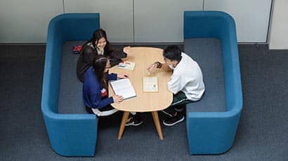 Three international students sitting in the Business School, working