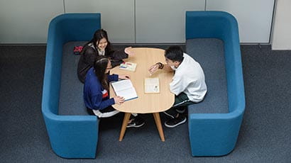 Three international students sitting in the Business School, working