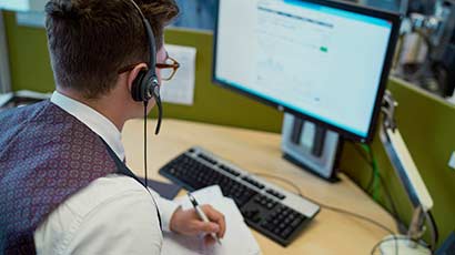 A work placement student at a desk, in front of a computer.