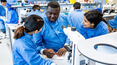 Three biomedical science students discussing results in a lab.