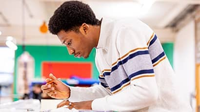 Architecture student leaning over a table and sketching.