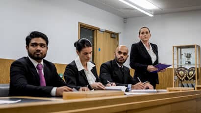 A group of trainee solicitors taking part in a simulation in a mock courtroom.